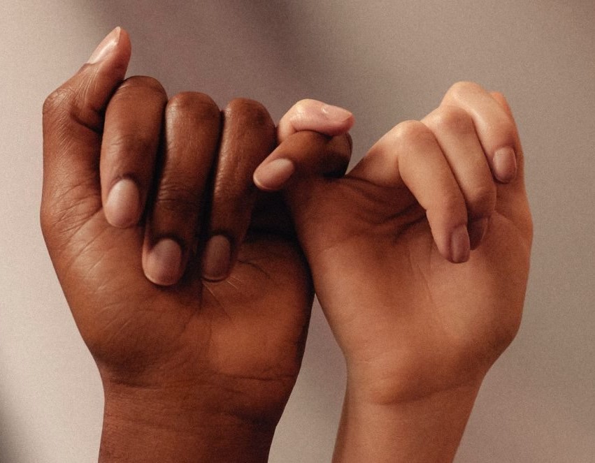 Two people with their pinky fingers interlocked