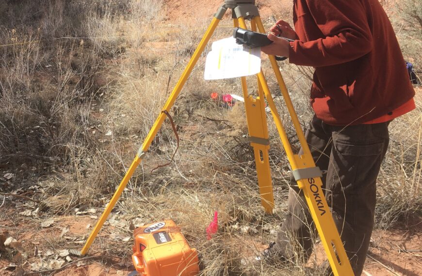 Photo of a man using a geographic survey tripod