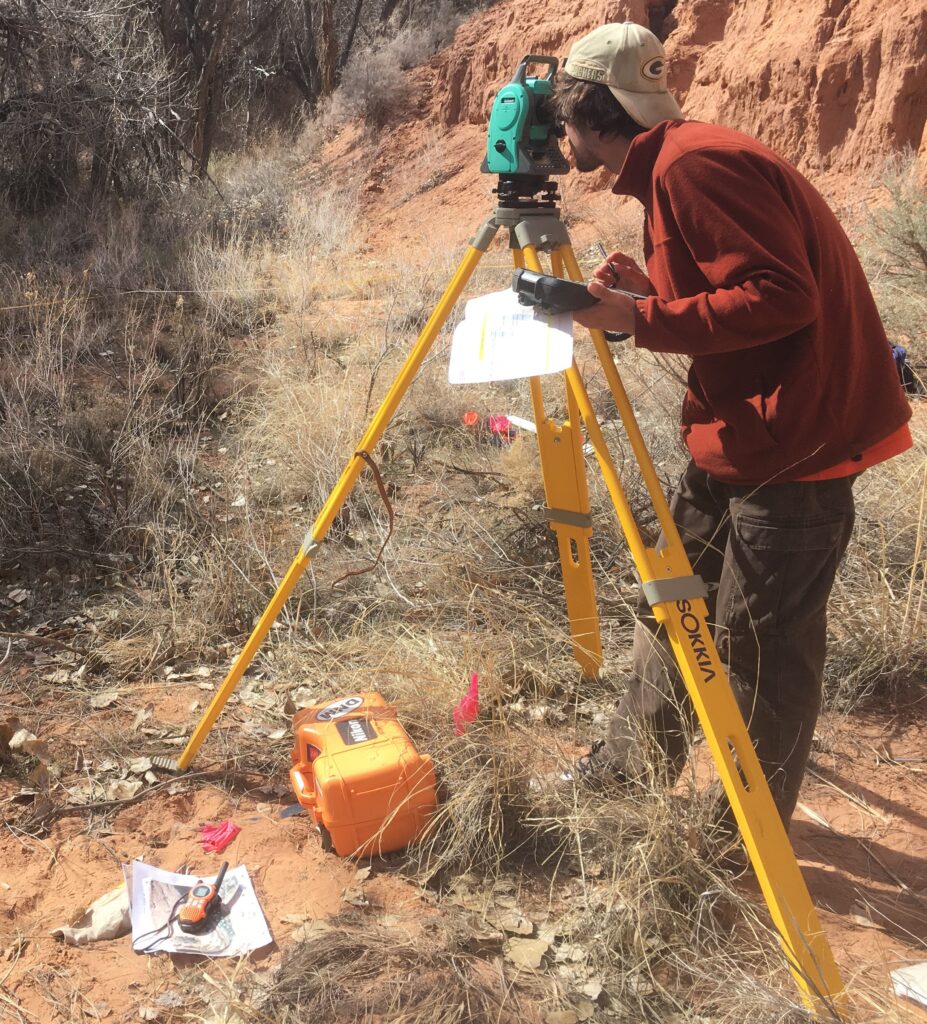 Photo of a man using a geographic survey tripod